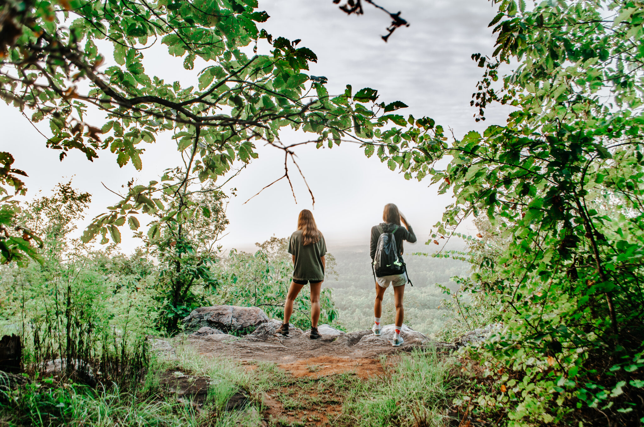 Two women on a hiking trail, overlooking the valley below